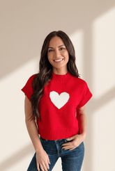 Woman wearing a red sweater with a white heart design against a beige background