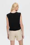 Woman wearing a black sleeveless top and beige shorts on a white background