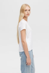 Person wearing a white t-shirt and light blue jeans on a plain background