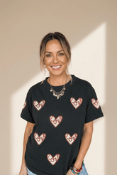 Woman wearing a black t-shirt with heart patterns against a beige background