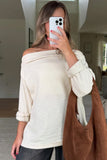 Person wearing a white off-shoulder top and holding a brown bag, taking a mirror selfie.