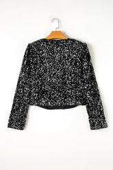 Black sequin top on a hanger against a white background