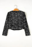 Black sequin top on a hanger against a white background