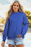 Woman wearing a blue sweatshirt with a blurred outdoor background