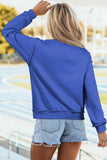 Person wearing a blue sweatshirt and denim shorts with a blurred outdoor background