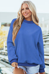 Woman wearing a blue sweater in a cozy living room setting.