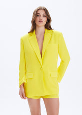 Woman wearing a bright yellow blazer on a white background