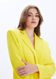 Woman wearing a bright yellow blazer against a white background