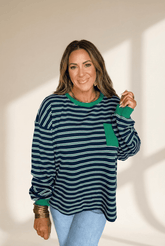 Woman wearing a striped sweater with green accents against a neutral background