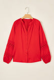 Bright red blouse with black embroidered lace cuffs on wooden hanger.