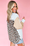 Woman wearing a leopard print and beige cardigan over a striped shirt on a pink background