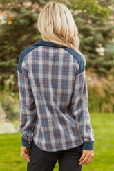 Person wearing a plaid shirt with a blurred natural background