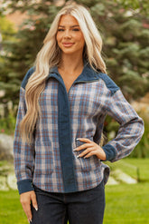 Woman wearing a plaid shirt with a blue hood in an outdoor setting