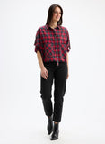 Woman wearing a red and black plaid shirt with black pants on a white background