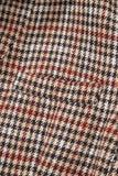 Close-up of a houndstooth pattern fabric with black, red, and beige colors.