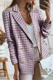 Person wearing a pink plaid blazer with gold buttons, holding a phone.
