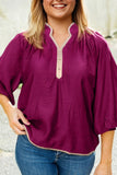 Woman wearing a purple blouse with a white collar and blue jeans against a neutral background