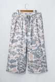 Gray, white, and dusty pink camouflage cropped wide-leg pants on a hanger.