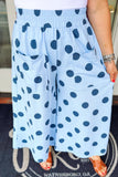 Person wearing light blue wide-leg pants with dark blue polka dots and front patch pockets.