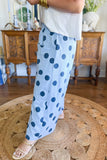 Person wearing light blue wide-leg polka-dot pants, white top, and beige sandals on a woven rug.