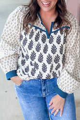 Woman wearing a floral blouse with blue accents and jeans, standing against a neutral background.
