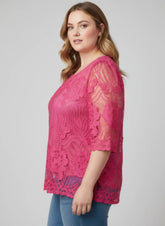 Woman wearing a pink lace top against a gray background