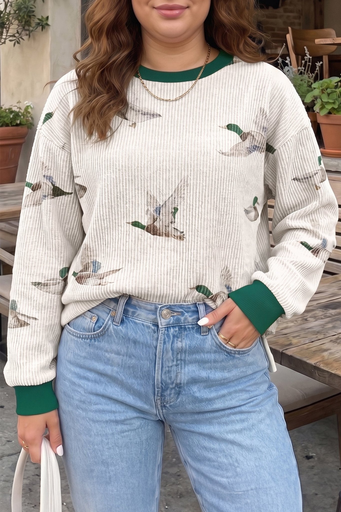Woman in ribbed sweater with green trim and mallard print, paired with jeans.
