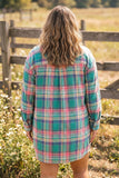 Woman wearing a green, pink, and blue plaid button-up shirt dress outdoors.
