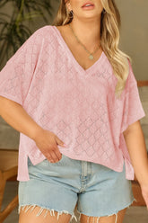 Woman wearing a pink textured top and denim shorts indoors.
