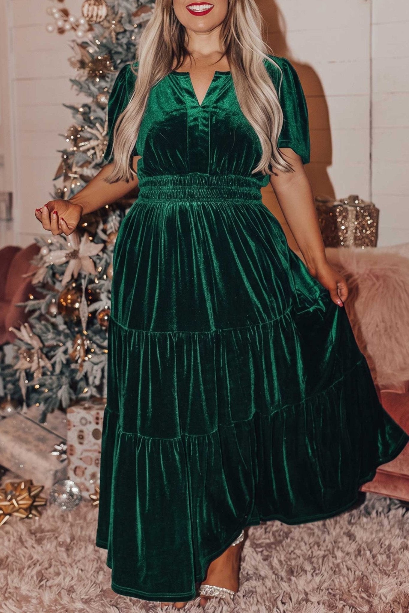 Woman in dark green velvet tiered maxi dress with puff sleeves and smocked waist.