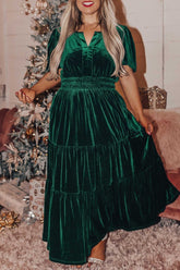 Woman in dark green velvet tiered maxi dress with puff sleeves and smocked waist.