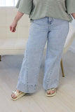 Person wearing rolled-cuff wide-leg jeans, striped top, and beige slides.