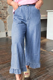 Woman in pink top, light blue ruffle-hem wide jeans, beige espadrille sandals.