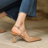 Beige high-heeled shoes worn with blue jeans on a neutral background