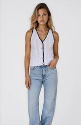 Woman wearing a white sleeveless top with black details and light blue jeans on a white background