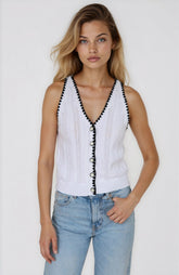 Woman wearing a white sleeveless top with black trim and blue jeans on a plain background