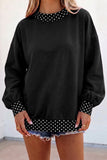 Women's black oversized sweatshirt with cream polka dot trim and balloon sleeves, front view