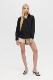 Woman wearing a black shirt and beige shorts on a white background