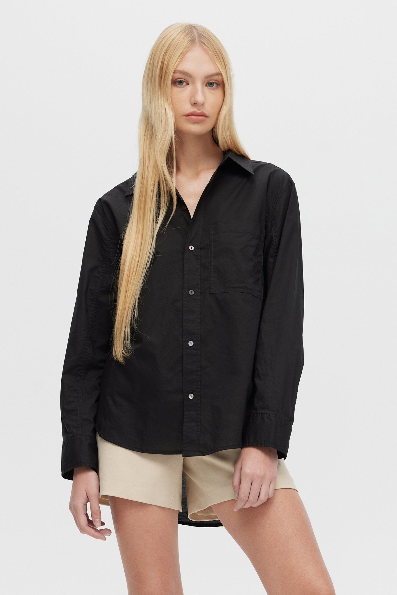 Woman wearing a black shirt and beige shorts on a white background