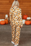 Woman wearing beige pumpkin-print pajamas with orange, black, and white jack-o'-lantern motifs.