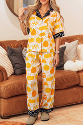 Woman in yellow and orange pumpkin-print pajamas by a brown leather couch.