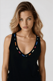 Woman wearing a black sleeveless top with colorful accents on a white background