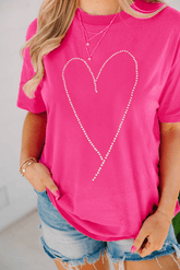 Person wearing a pink t-shirt with a heart design, standing against a white background