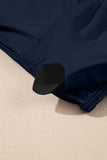 Navy blue ribbed fabric with black curved trim on a beige surface.