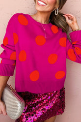 Woman in pink polka-dot sweater & sequined skirt with clutch.