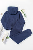 Navy blue hoodie and pants set on a white background with a plant and magazine.