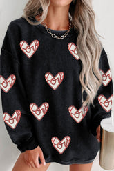 Black sweater with red heart patterns worn by a person with long blonde hair.
