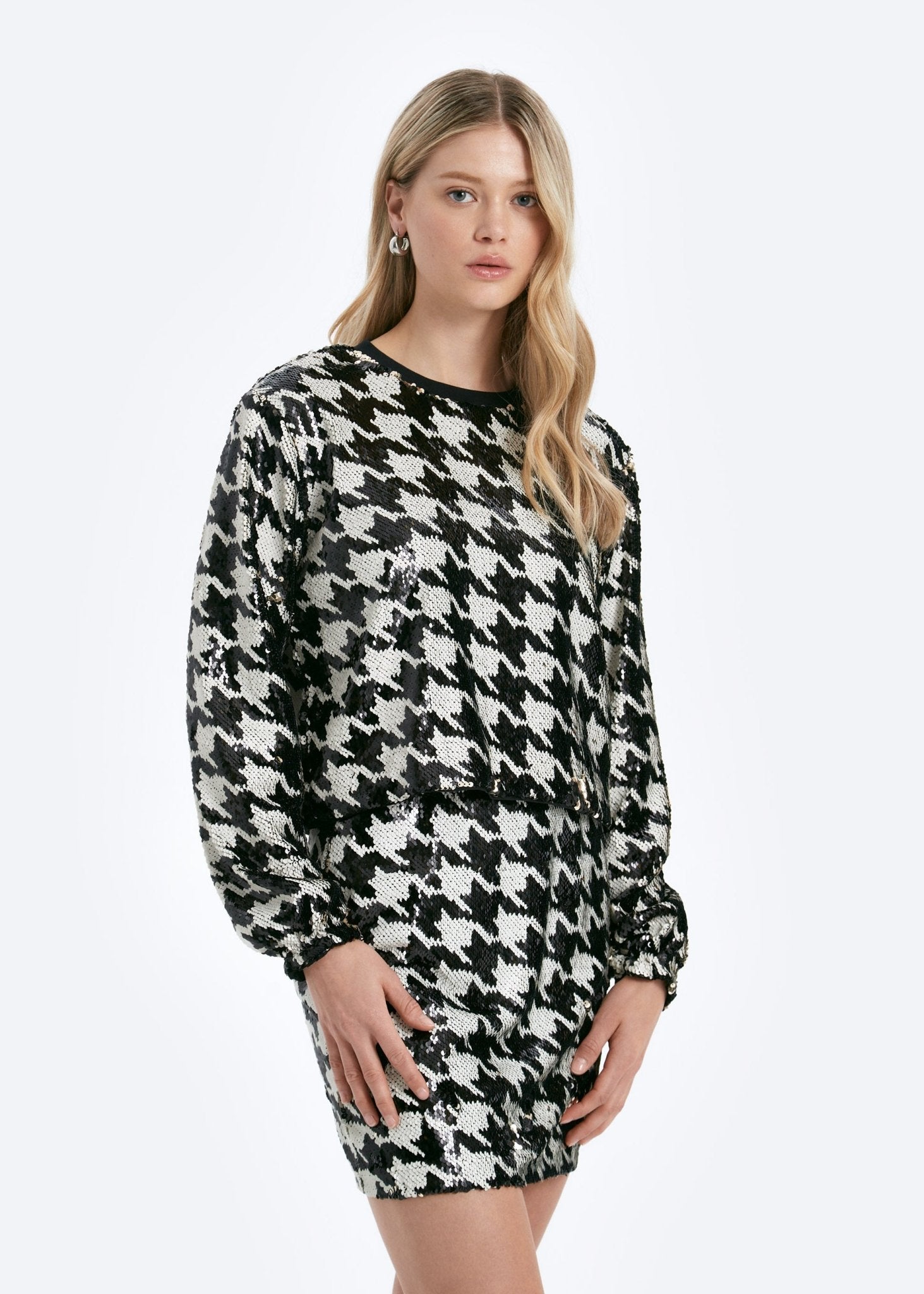 Woman wearing a black and white houndstooth pattern dress on a light gray background