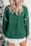 Woman wearing a dark green knit sweater with white stitching and a white skirt.