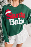 Woman wearing a festive green “Santa Baby” sweater with white shorts.